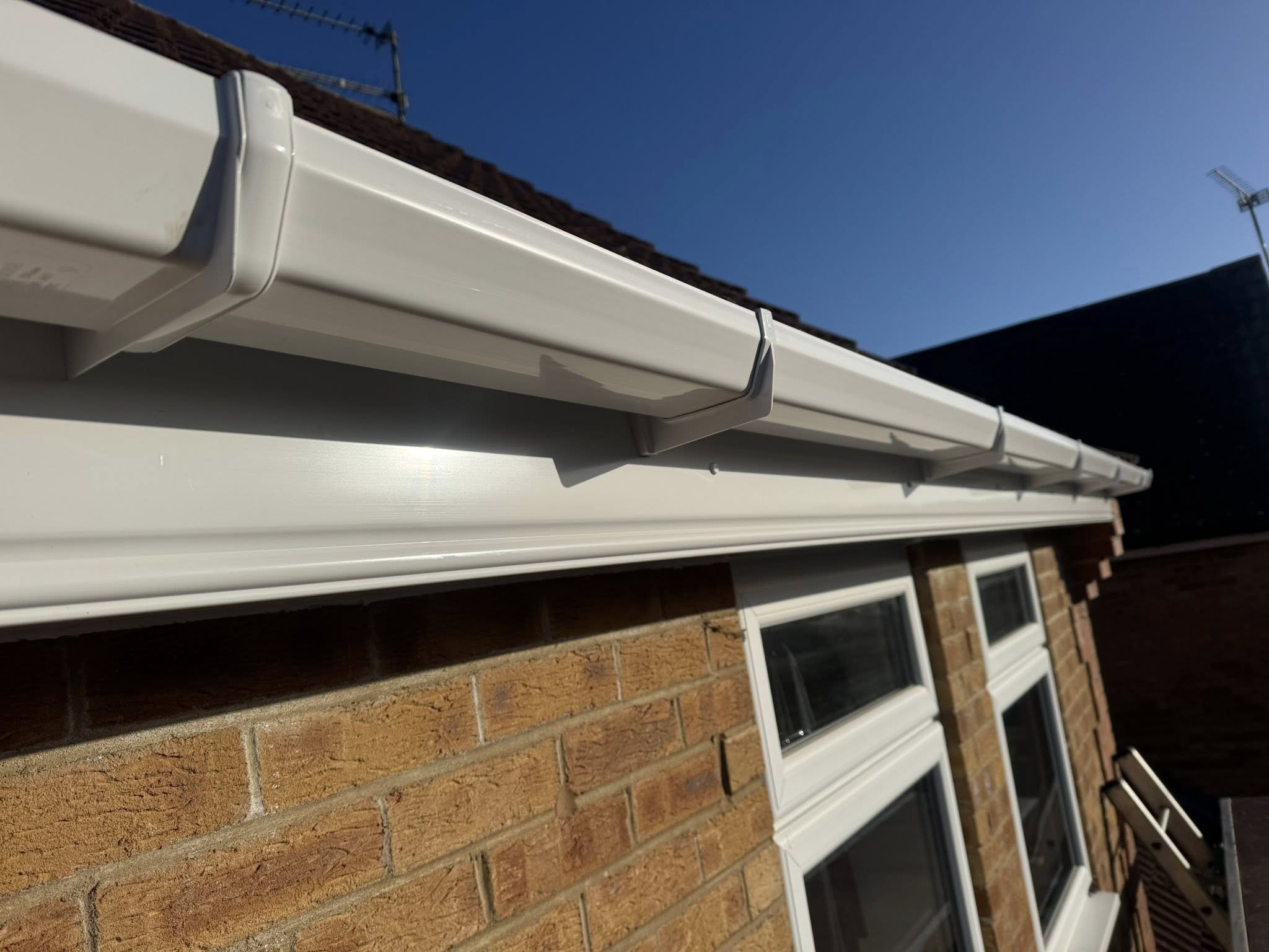 Newly installed white uPVC guttering on a brick home