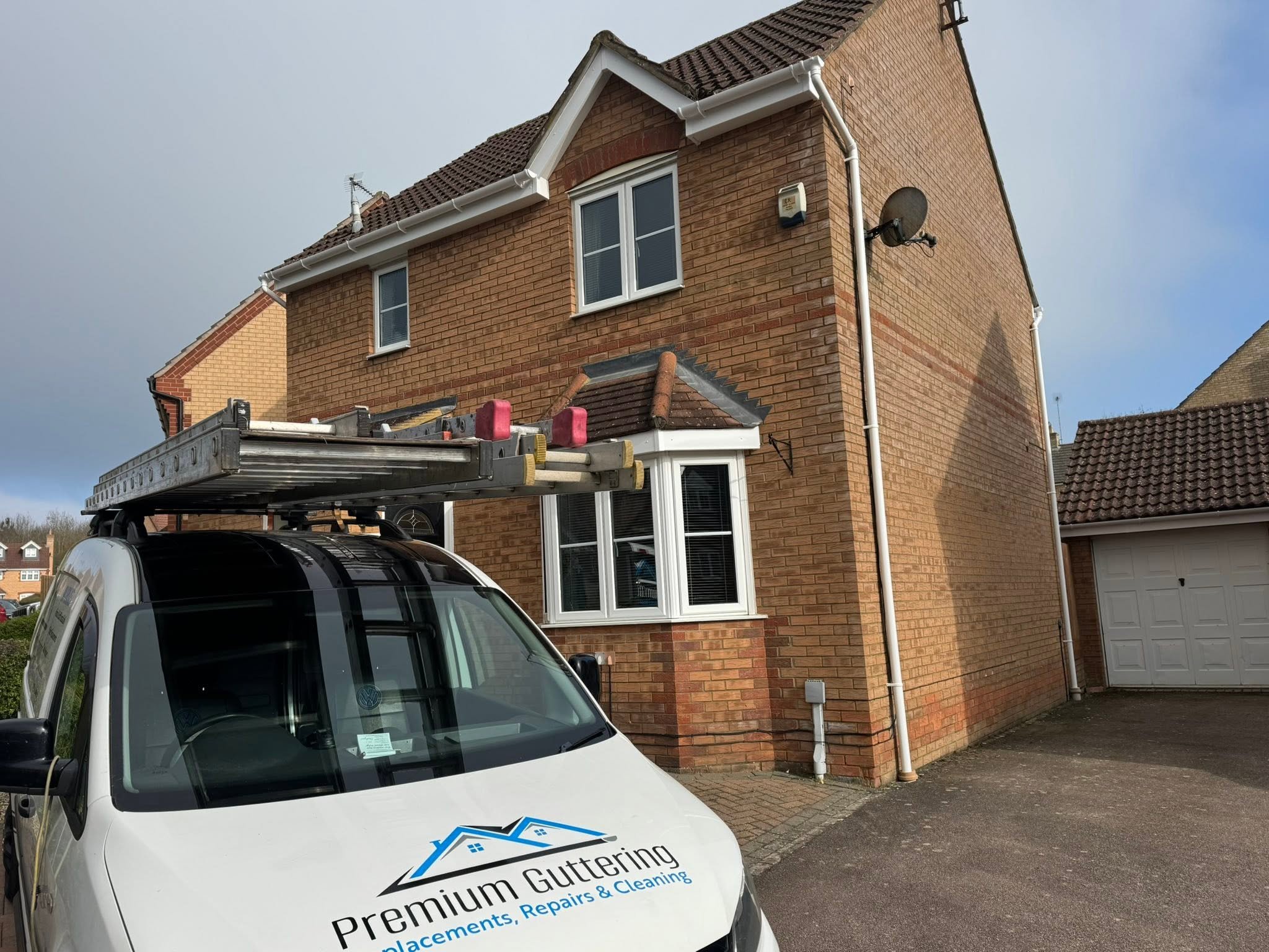 Premium Guttering service van outside a brick home